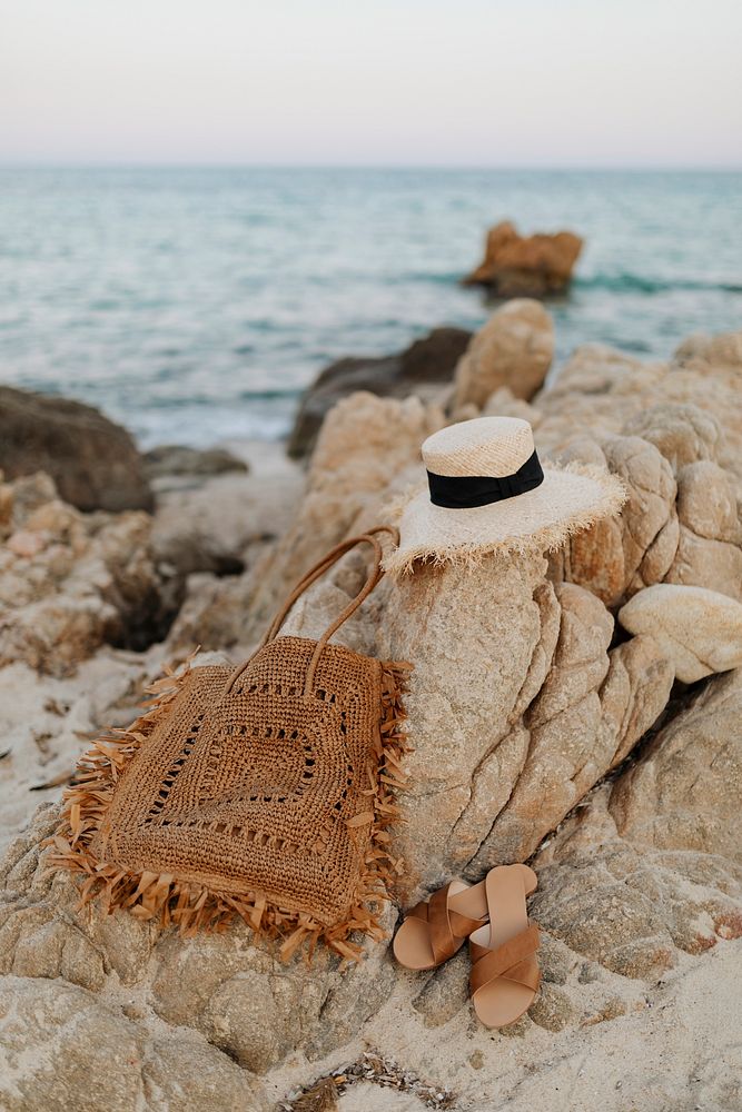 Straw hat and a woven bag on a rocky beach