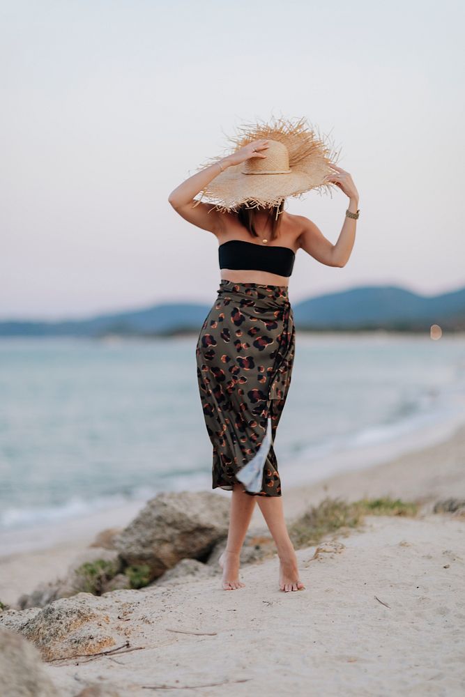 Woman wearing a straw hat walking alone the beach