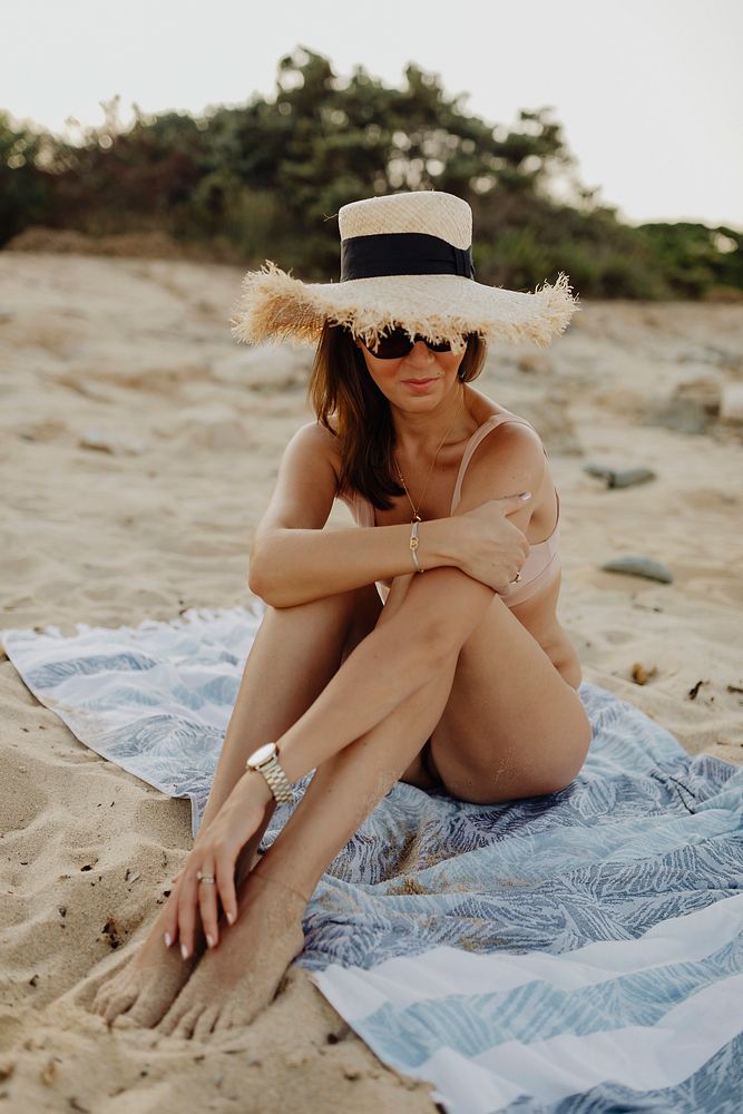 Girl with a straw hat sitting at the beach