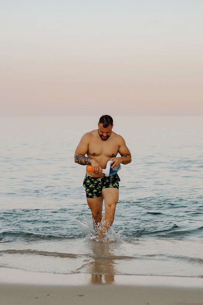 Man walking up from the sea with snorkel mask in his hands