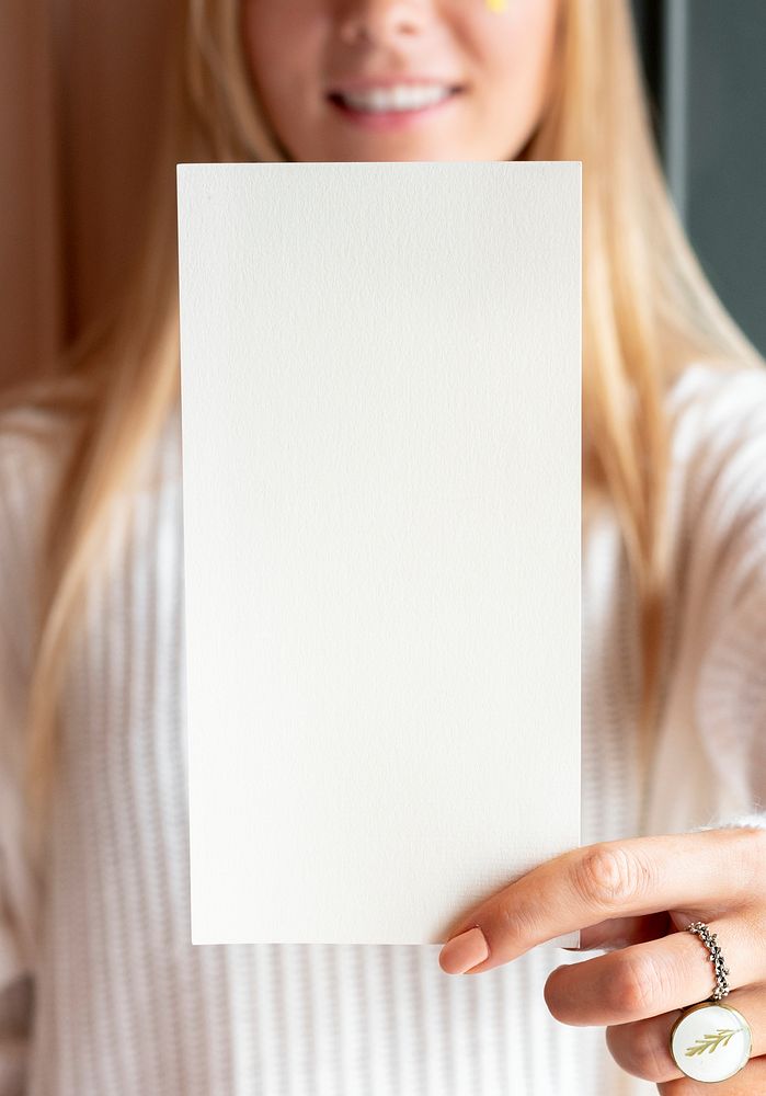 Woman in a white sweater holding a card mockup