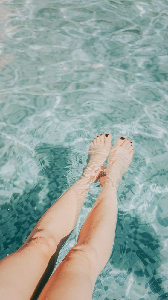 Woman putting her legs in the pool mobile phone wallpaper