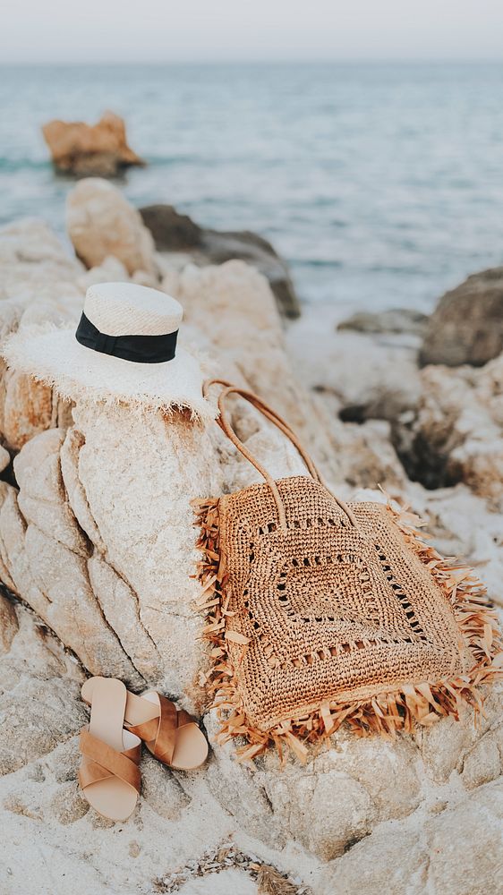 Straw hat and a woven bag on a rocky beach mobile phone wallpaper