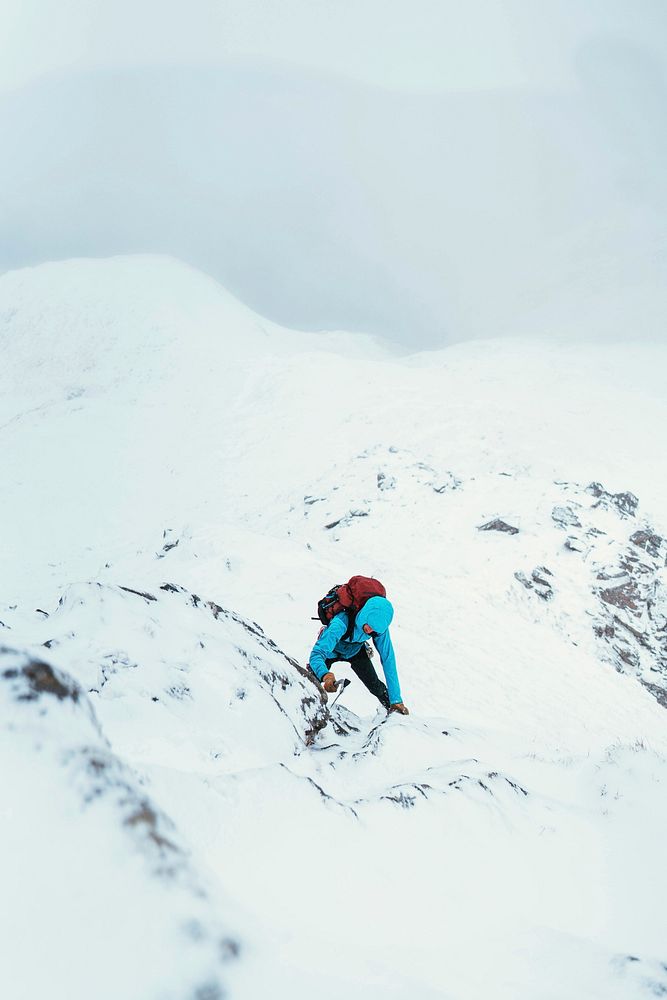 Mountaineer using an ice axe  to climb Forcan Ridge in Glen Shiel, Scotland