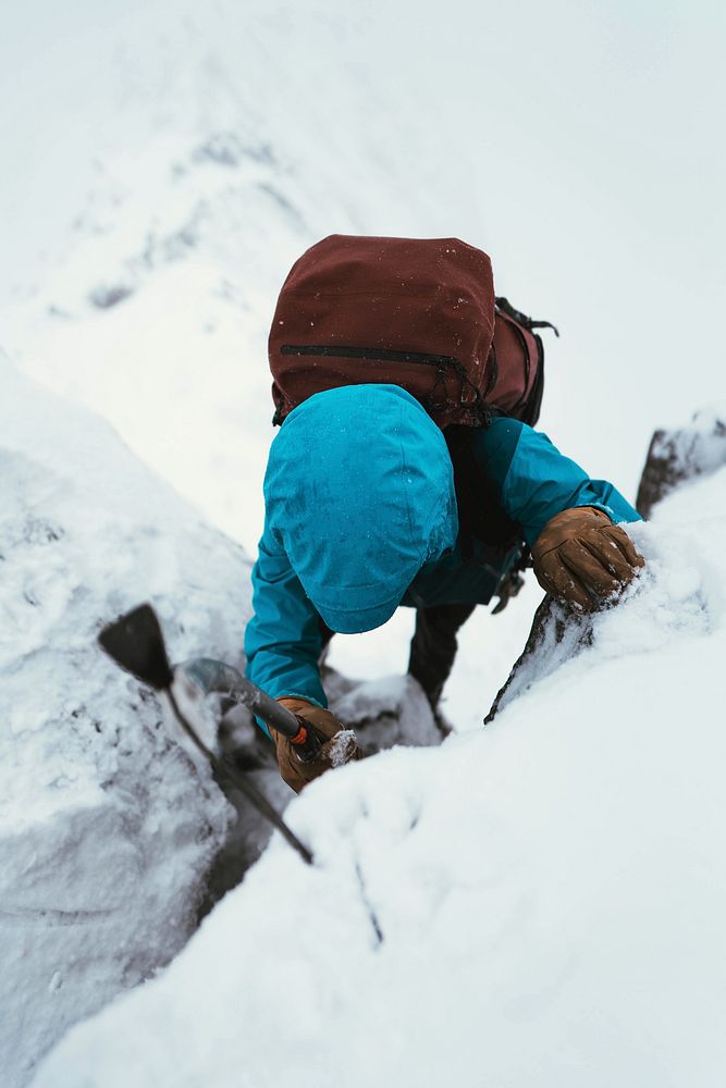 Mountaineer using an ice axe to climb Forcan Ridge in Glen Shiel, Scotland
