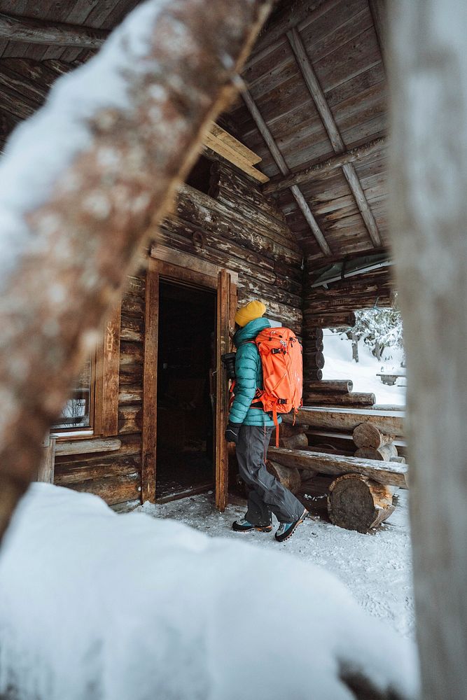Female photographer entering a cabin in the snowy woods