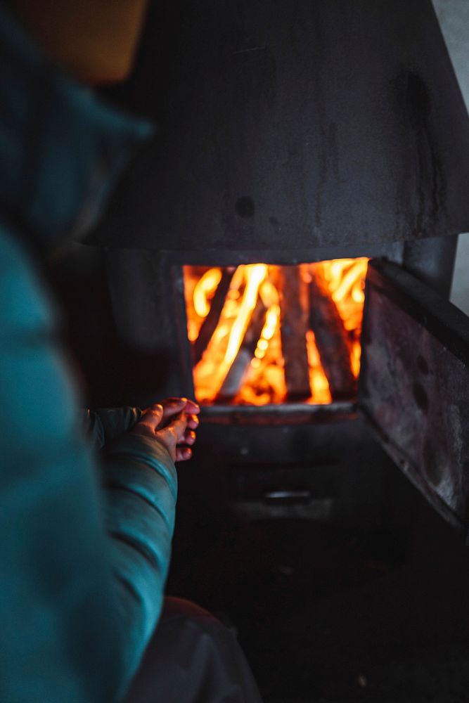 Woman warming up near a fireplace in a hut