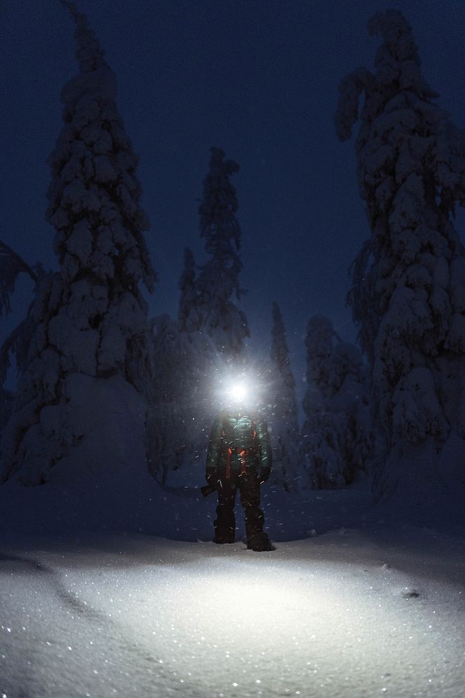 Trekker with a headlamp walking in a snowy Riisitunturi National Park, Finland