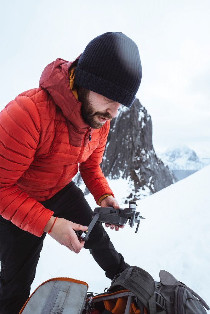 Backpacker setting up a drone in the snowy Segla mountain, Norway