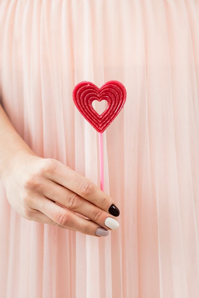 Woman holding a red heart on a stick  