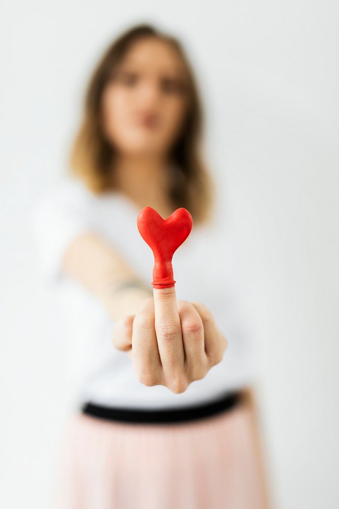 Red heart balloon on a middle finger