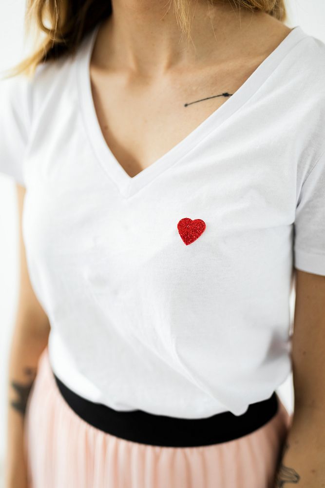 Tattooed woman in a white t-shirt with a little heart 