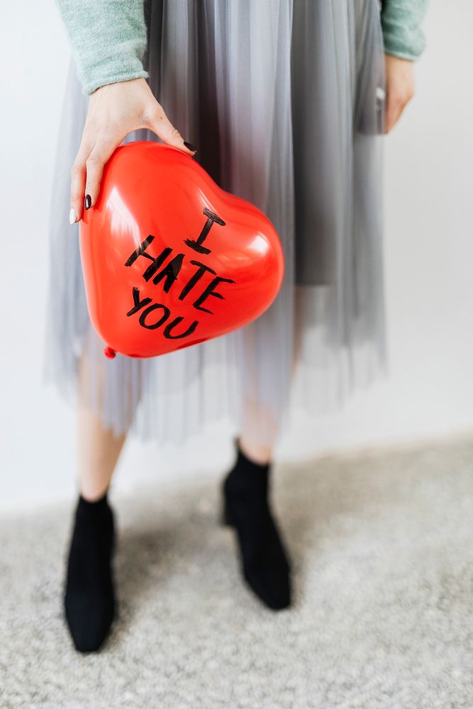 Woman showing a heart red balloon with I hate you on it