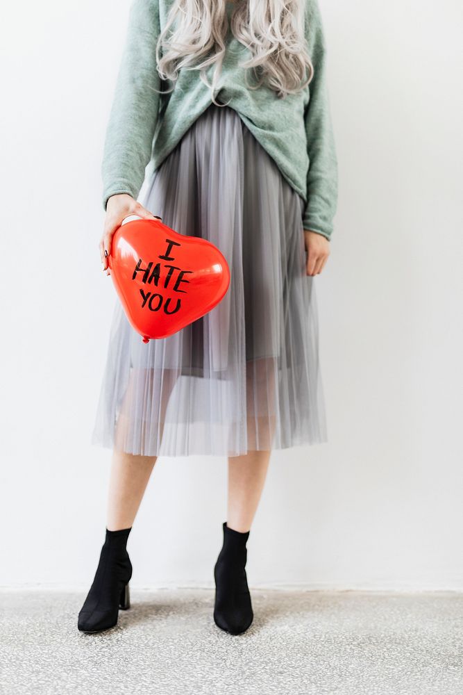 Woman showing a red heart balloon with I Hate You text