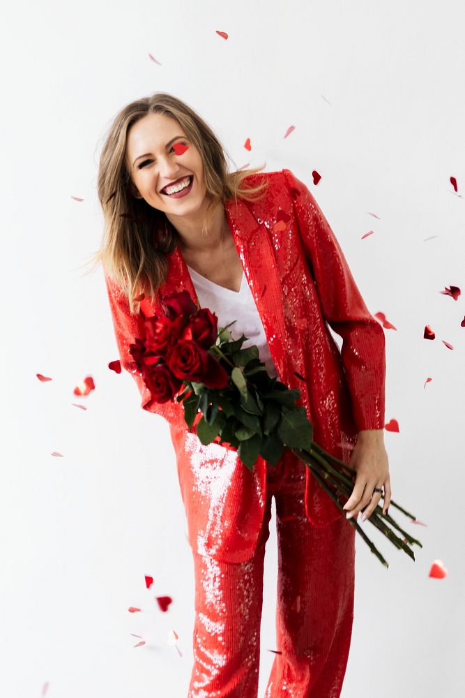Happy woman in a red pantsuit with a bouquet of roses 