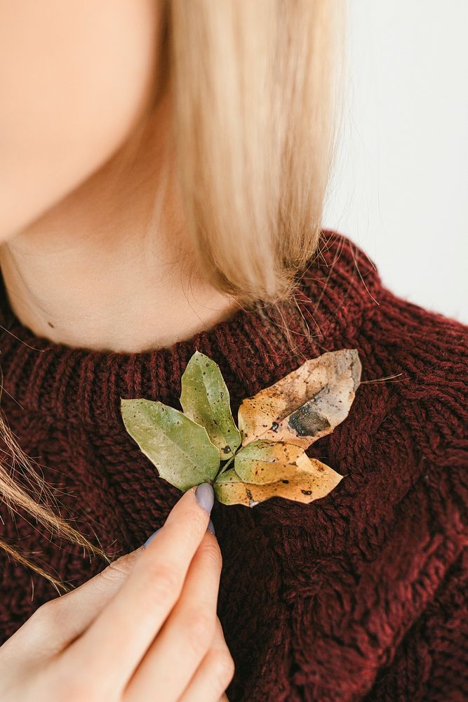 Woman in a sweater holding crisp leaves during fall season
