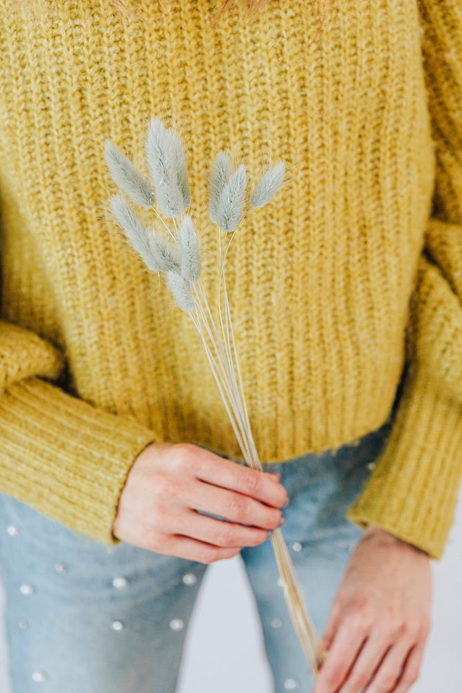 Woman in a yellow sweater holding a hare's tail grass 