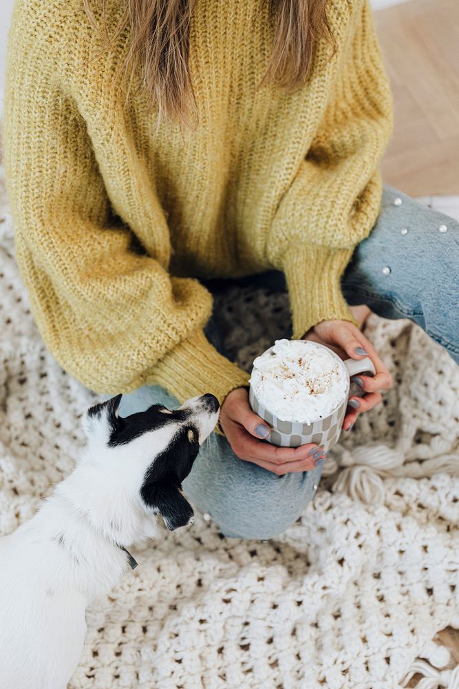 Woman at home with her pet dog drinking hot chocolate with whipped cream