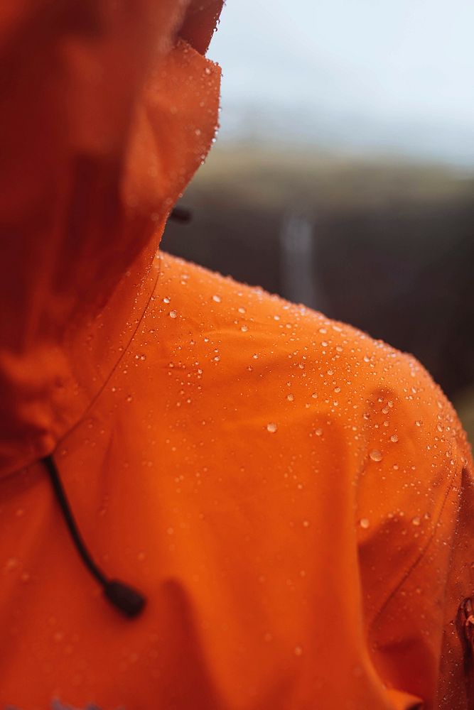 Man wearing an orange windbreaker in the rain at the Faroe Islands