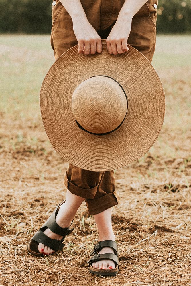 Woman holding a wide brim straw hat psd