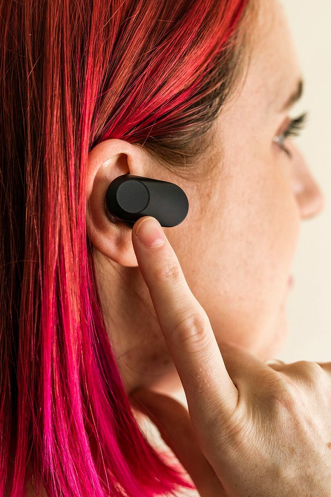 Woman with pink hair wearing wireless earbuds