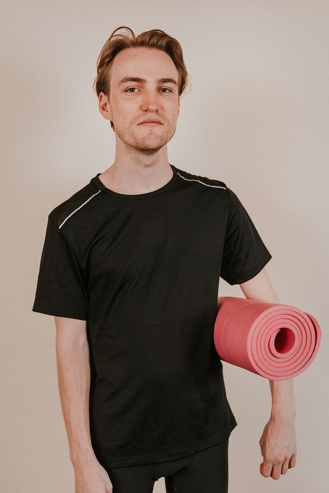 Man in black sport shirt with pink yoga mat studio shot