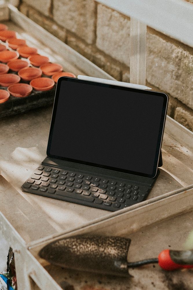 Psd black tablet screen mockup with keyboard on a gardening wooden table