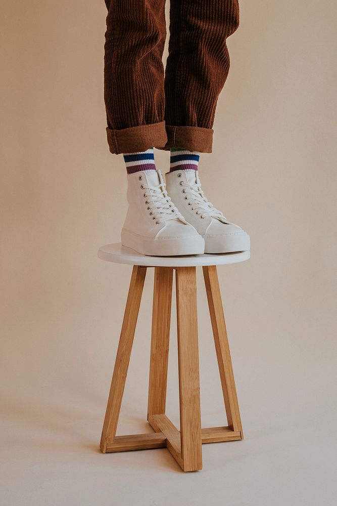 Model in white high top sneakers standing on chair