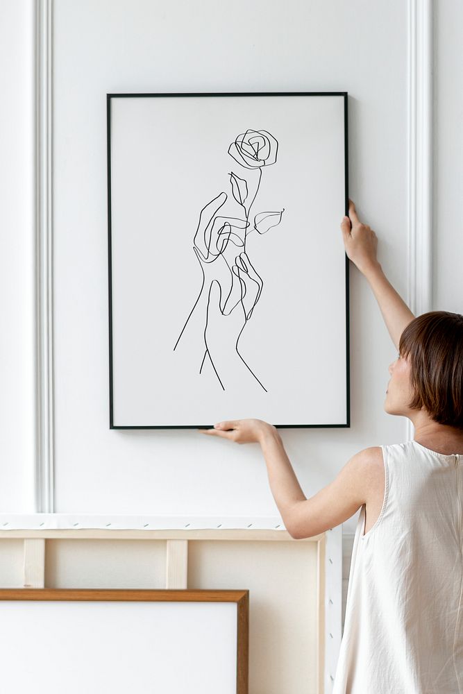 Woman arranging frame mockup psd on a wall in a Japandi decor room