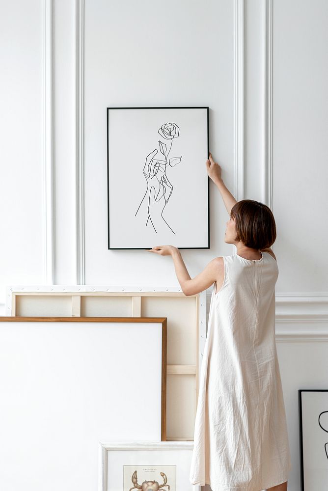 Woman arranging frame on a wall in a Japandi decor room