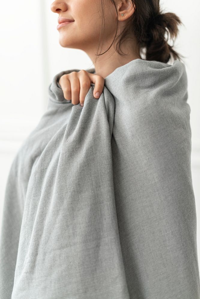Woman wrapped around with gray throw blanket in winter