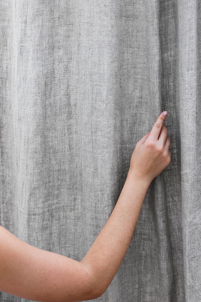 Woman closing a gray curtain in a living room
