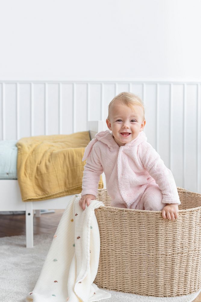 Little girl climbing in a laundry basket