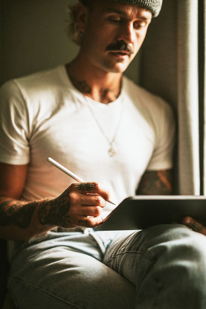 Alternative man in white tee using digital tablet