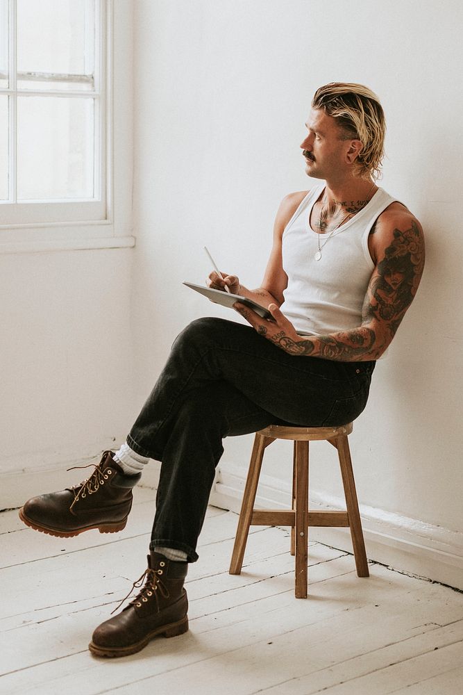 Fashionable man in white tank top using digital tablet