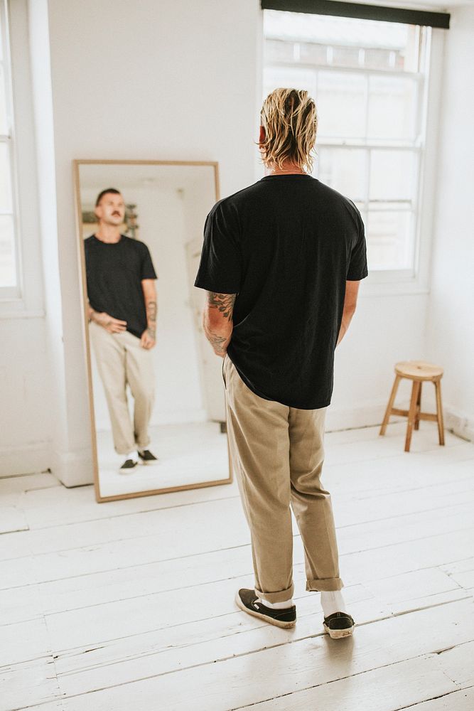Fashionable man looking at himself in the mirror