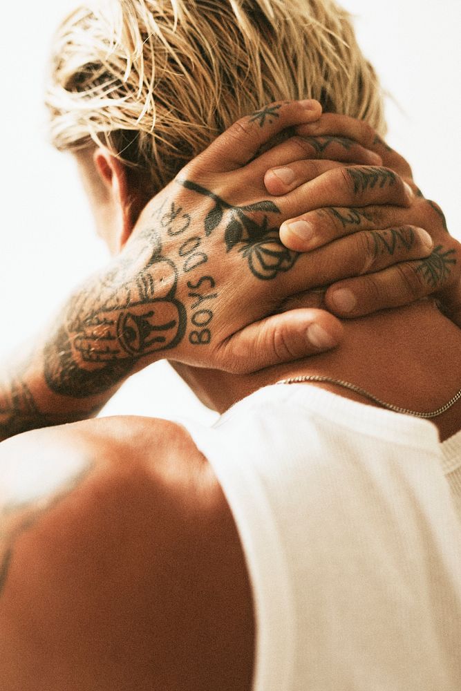 Tattooed blonde man clasping his hands in his neck. 2 OCTOBER 2020 - CHIPPENHAM, UK