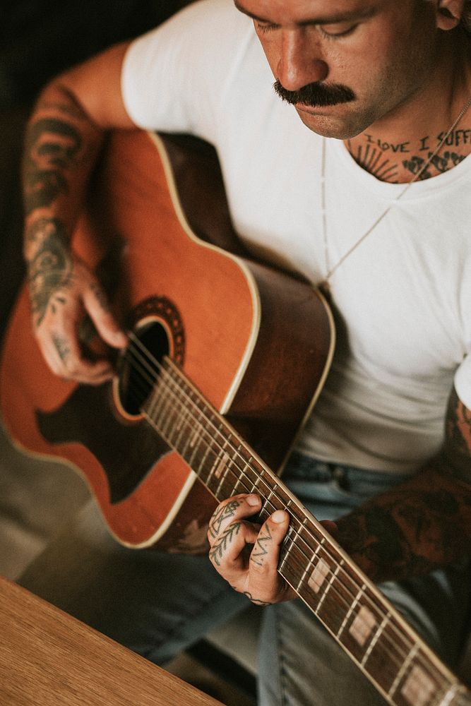 Tattooed singer songwriter playing an acoustic guitar