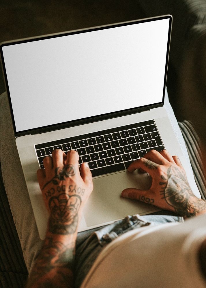 Tattooed man working on laptop screen mockup