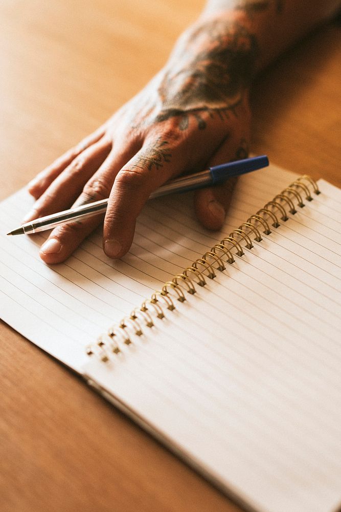 Cool tattooed man writing in a notebook