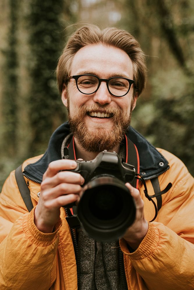 Photographer man smiling while holding camera in the woods