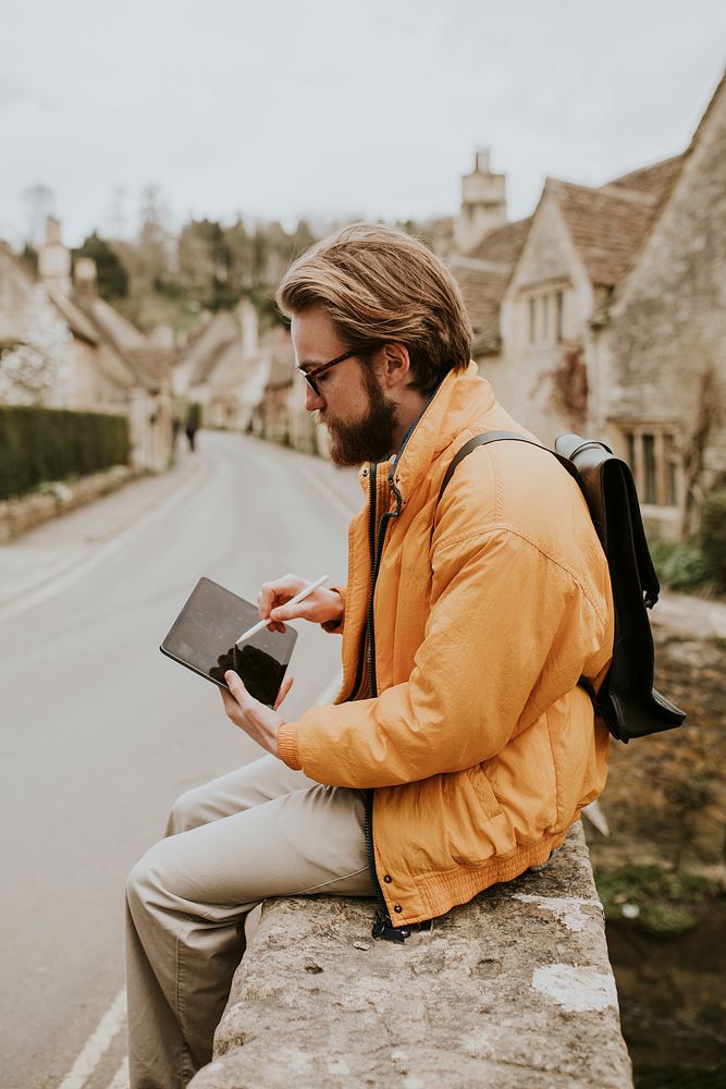 Man taking notes on his tablet in Cotswolds village, UK