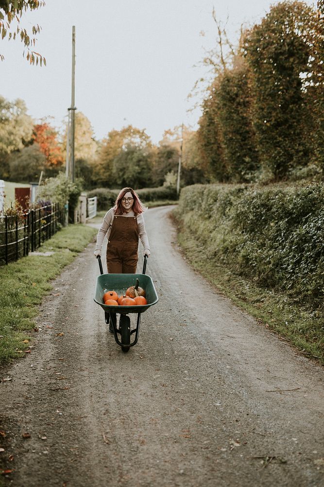 Woman with Halloween pumpkin wheelbarrow dark autumn mood