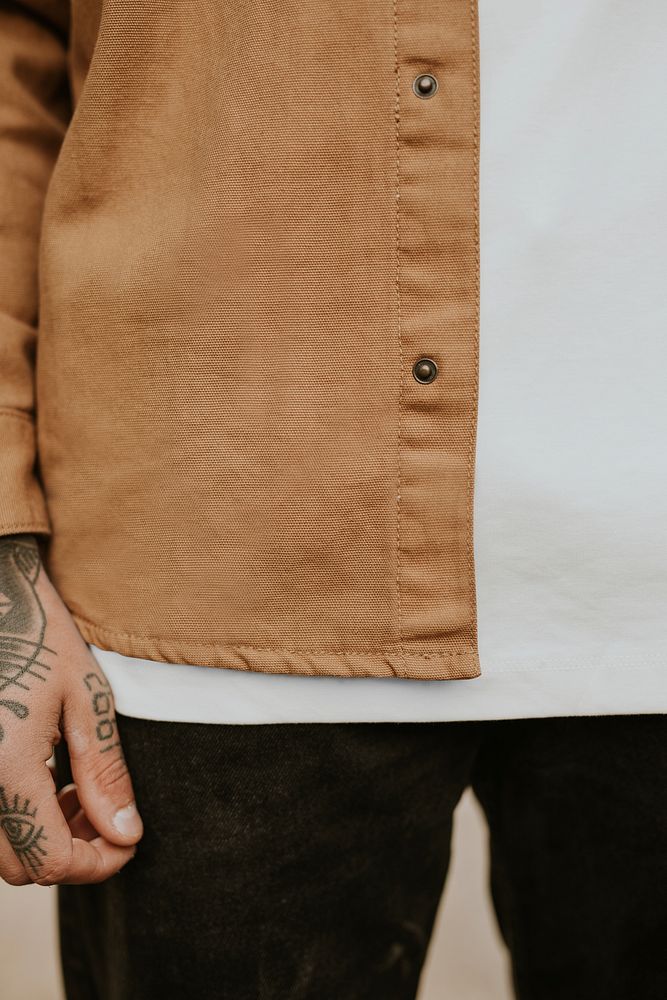 Tattooed man wearing his brown shirt closeup