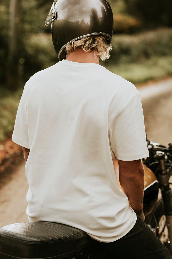 Blonde man in white t-shirt sitting on a bike with design space