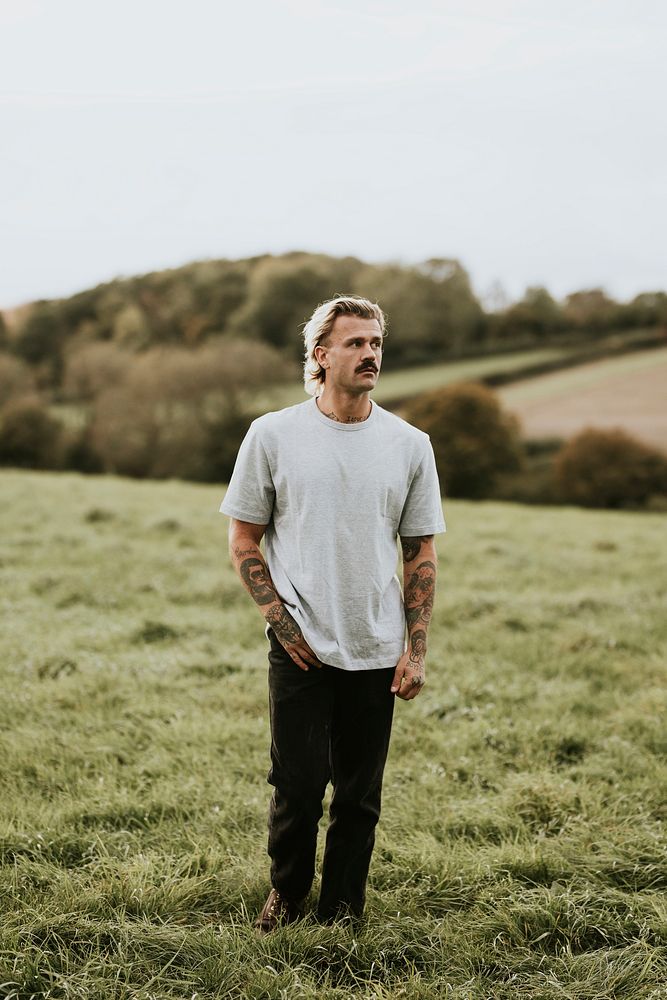 Attractive man in gray t-shirt with design space standing in countryside