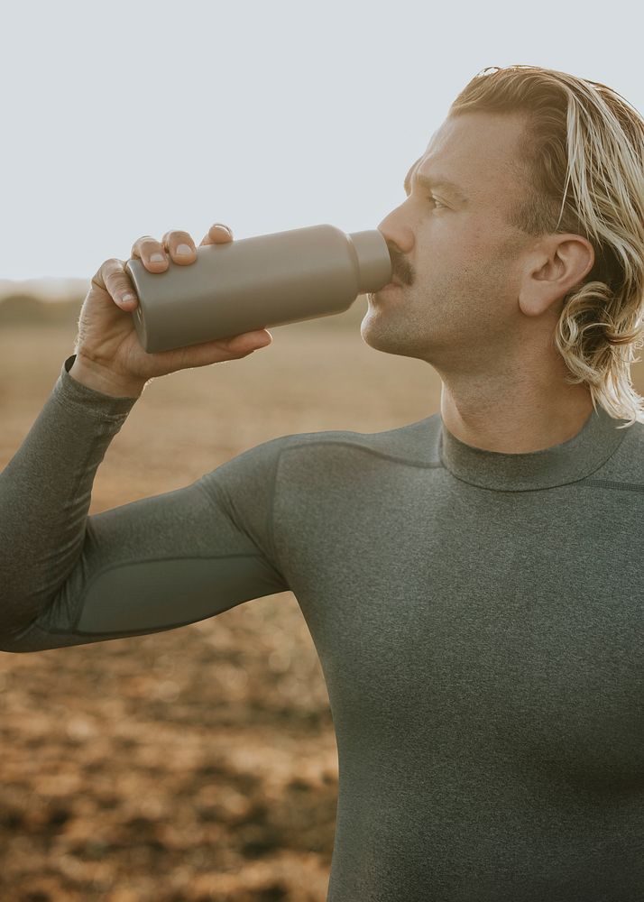 Man drinking water from stainless steel bottle after working out