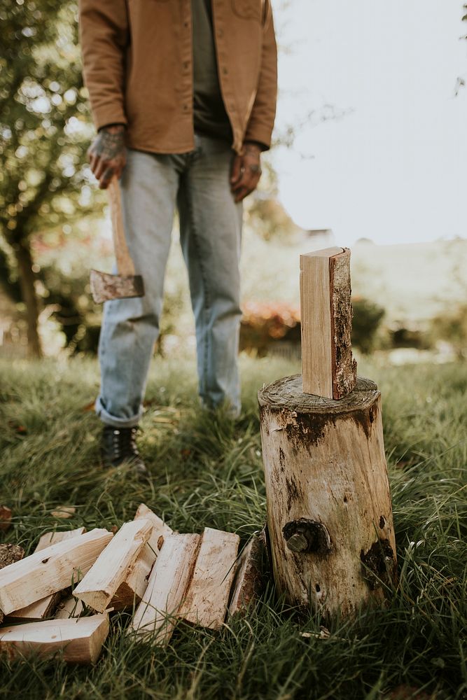 Country man splitting wood with axe on the field