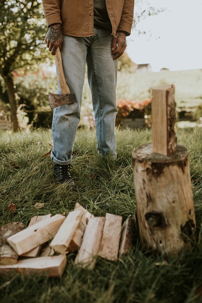 Country man splitting wood with axe on the field