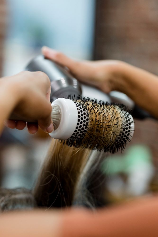 Hairstylist blow drying the customer's hair